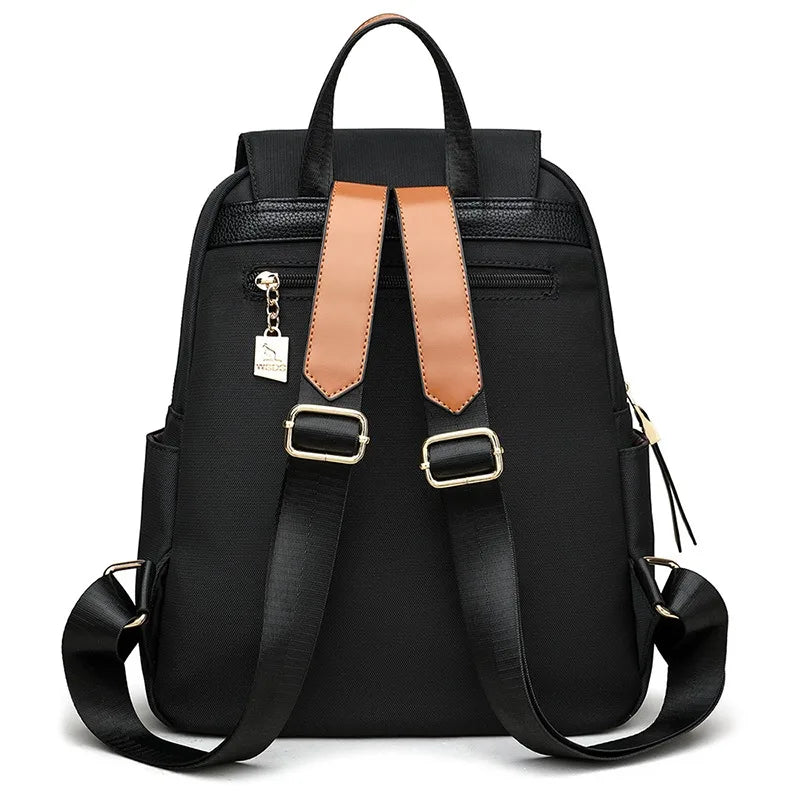 Back view of a black Oxford backpack showing adjustable shoulder straps and gold-tone hardware.