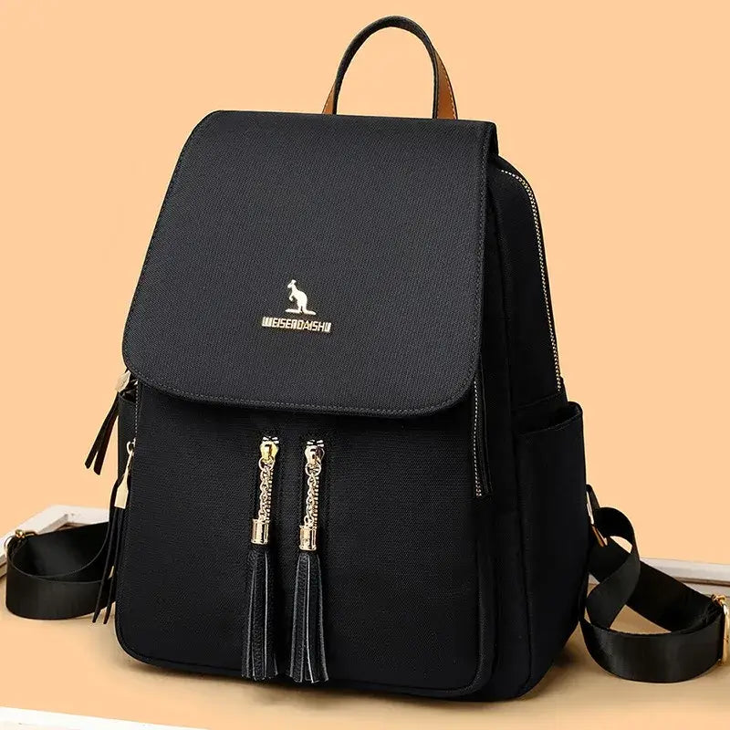 Black Oxford backpack displayed against a beige background with gold-tone zipper details.
