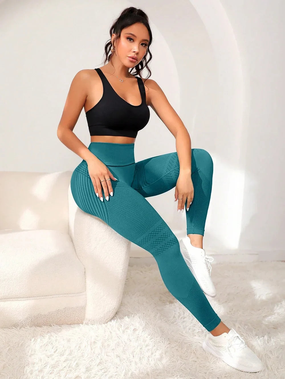 Teal high-waisted textured leggings paired with a black cropped top and white trainers.