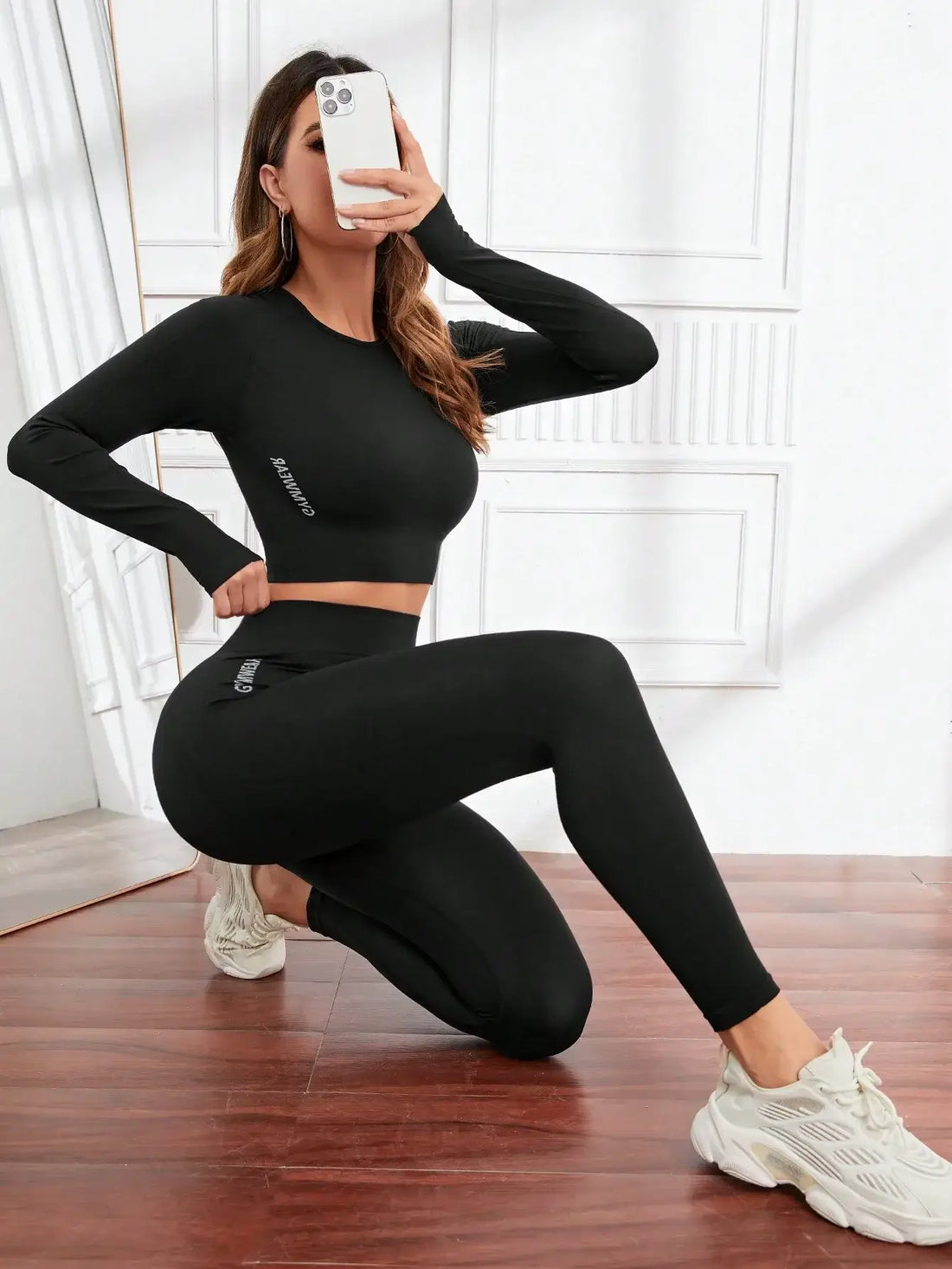 Woman posing on one knee in a black long sleeve crop top and leggiSeamless Leggings Set in black modeled in a kneeling pose with long sleeve crop topngs set.