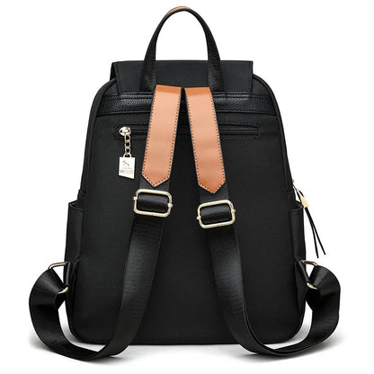 Back view of a black Oxford backpack showing adjustable shoulder straps and gold-tone hardware.