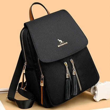 Black Oxford backpack with front flap, gold-tone zippers, and adjustable shoulder straps.