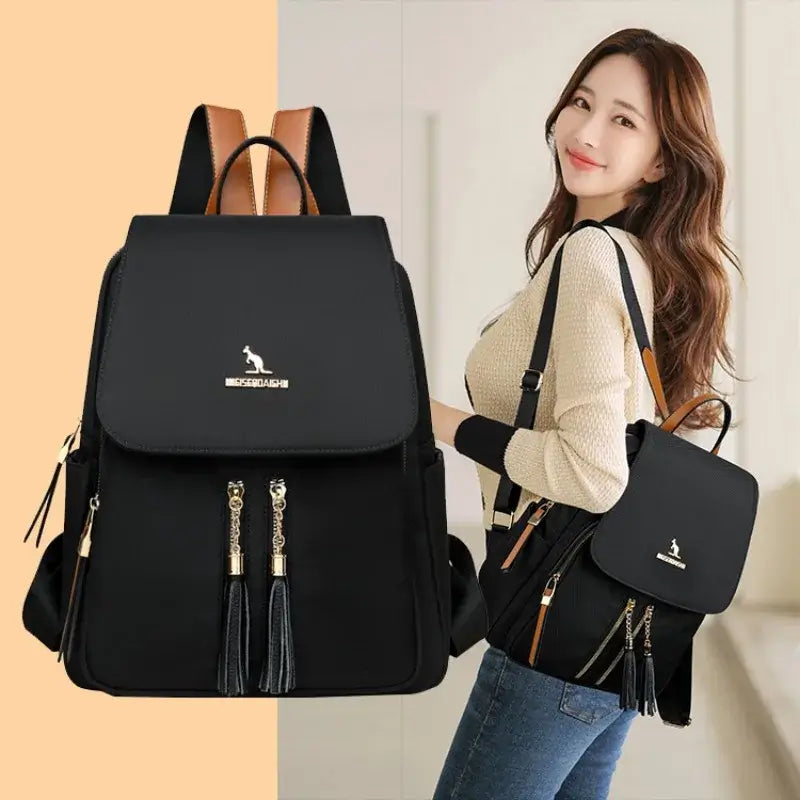 Woman carrying a black Oxford backpack with gold-tone zippers and a matching shoulder bag.