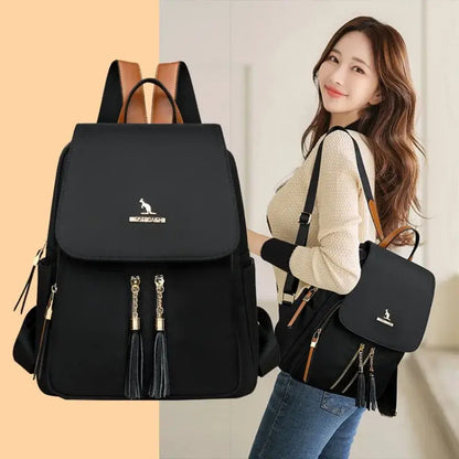 Woman carrying a black Oxford backpack with gold-tone zippers and a matching shoulder bag.