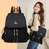 Woman carrying a black Oxford backpack with gold-tone zippers and a matching shoulder bag.