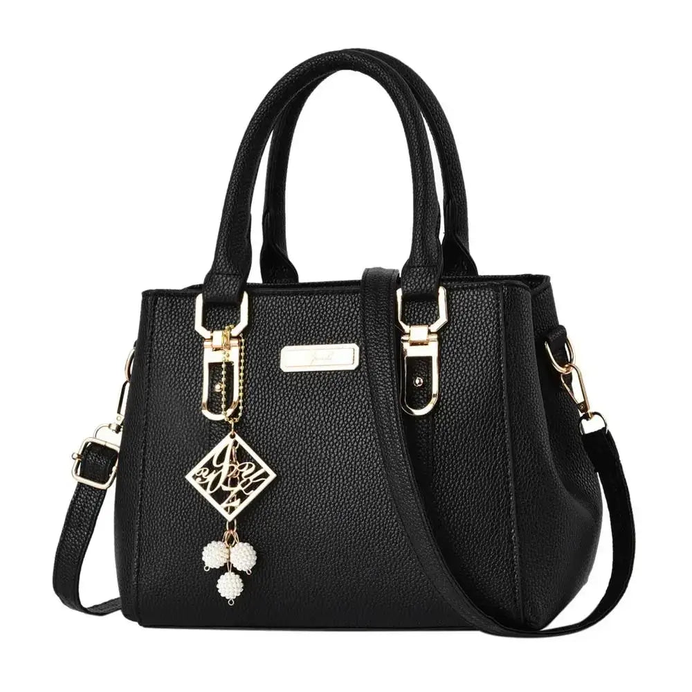 Black structured handbag with top handles, gold-tone hardware, and decorative charms.