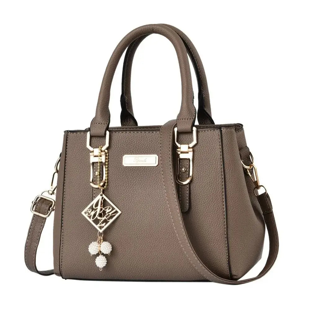 Brown structured handbag with top handles, a shoulder strap, and gold-tone accents.