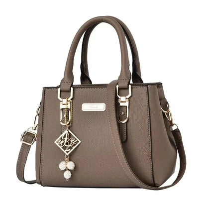 Brown structured handbag with top handles, a shoulder strap, and gold-tone accents.