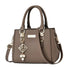 Brown structured handbag with top handles, a shoulder strap, and gold-tone accents.