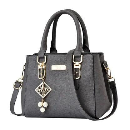 Gray structured handbag shown from an angled side view with gold-tone details.