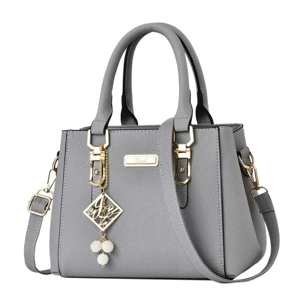 Gray structured handbag with top handles, gold-tone hardware, and decorative charms.