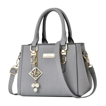 Gray structured handbag with top handles, gold-tone hardware, and decorative charms.